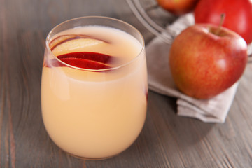 Glass of apple cider with fruits on wooden background