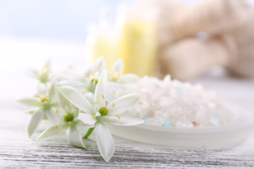 Fototapeta na wymiar Sea salt, flowers and spa treatment on color wooden table, on light background