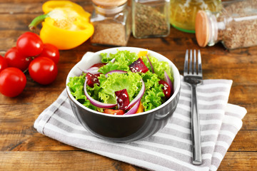 Bowl of fresh green salad on table with napkin, closeup