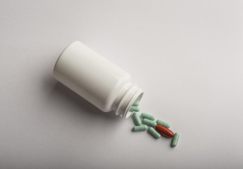 Colorful pills and pill bottle on white background