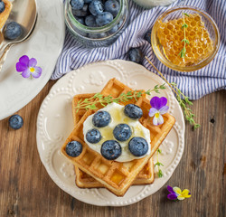 Homemade fresh crispy waffles for breakfast with blueberries and honey