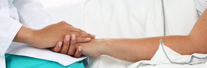 Fototapeta premium Friendly female doctor hands holding patient hand