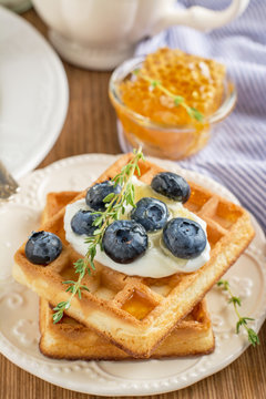 Homemade fresh crispy waffles for breakfast with blueberries and honey