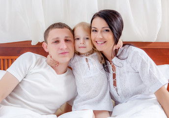 Happy family lying on a bed together in the bedroom