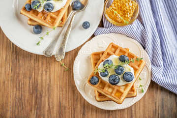 Homemade fresh crispy waffles for breakfast with blueberries and honey