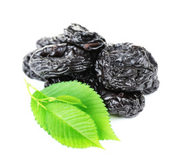 Pile of prunes with green leaves isolated on white