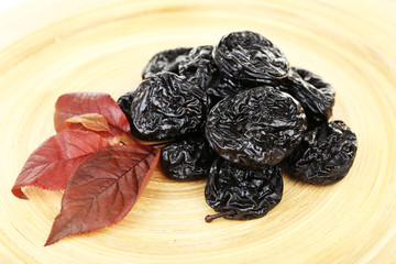 Pile of prunes with leaves on wooden background