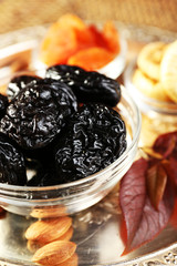 Prunes and other dried fruits in glass with grape leaves saucers, closeup