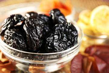 Pile of prunes in glass saucers with grape leaves, closeup