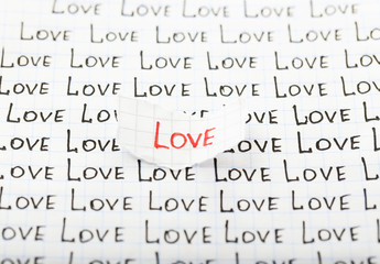 Word LOVE written on torn paper on sheet of paper background