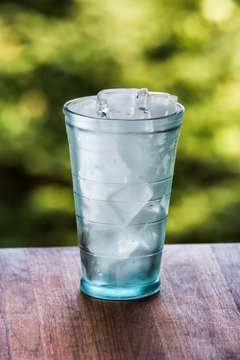 Full glass of water with ice on the wooden kitchen counter. Wodd