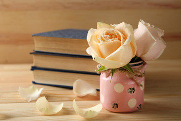 Fresh roses with old books on  wooden background. Vintage concept