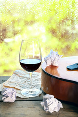 Acoustic guitar and glass of wine next the window with rain drops