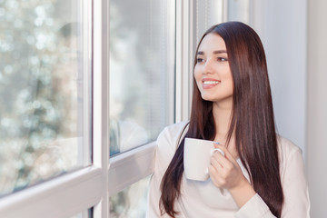 Pleasant woman standing near window 