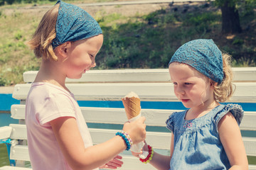 Little cute girls (sisters) eat ice cream. Selective focus.