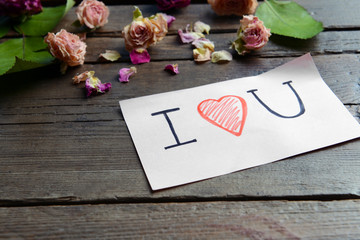 Written message with dry flowers on wooden table close up