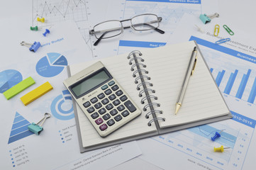 Book, pen, calculator, glasses on financial chart