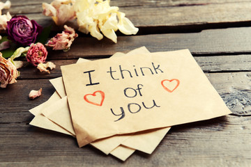 Written message with dry flowers on wooden table close up