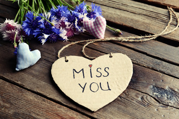 Written message with dry flowers  and decorative hearts on wooden table close up