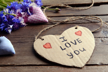 Written message with dry flowers  and decorative hearts on wooden table close up