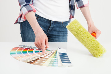 Unrecognizable woman examining palette and holding a roller