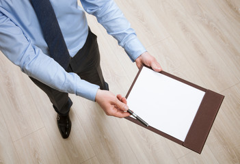 Businessman holding a clipboard with empty sheet of paper and pr