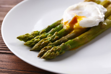 Roasted asparagus with poached egg on plate on table close up
