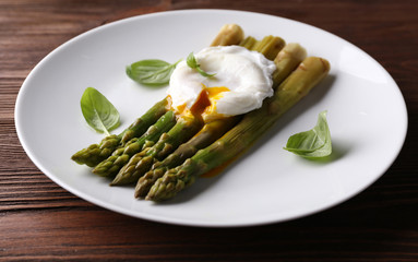Roasted asparagus with poached egg on plate on table close up