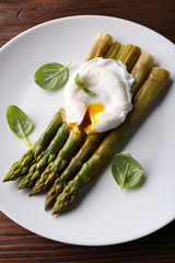 Roasted asparagus with poached egg on plate on table close up