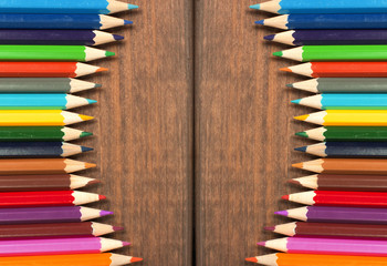 Multicolored pencils on a background of dark wood tables