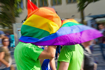 Zwei Männer auf dem auf dem Christopher Street Day mit Regenbogenfahne 