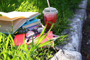 Obraz na płótnie Canvas Books, glasses and drink on grass close-up