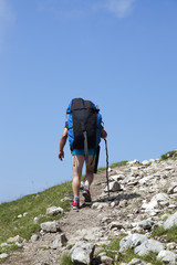 Paraglider,  trekker, mountaineer, walking up hill to a paragliding starting point, on a sunny morning, high in the mountains, space for text