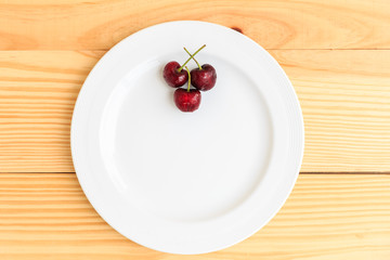Placed cherry in the dish on the wood