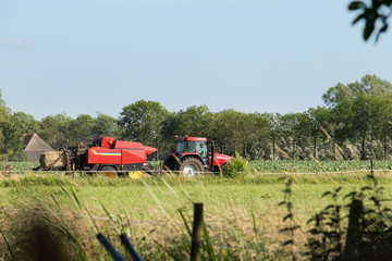 Gedroogd gras wordt door een loonbedrijf in balen geperst in een weiland in Zwolle, Overijssel...