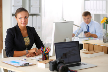 Fashion designers working in studio sitting on the desk