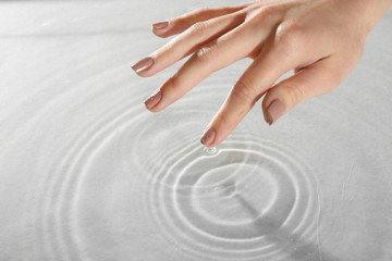 Female hand touching water surface