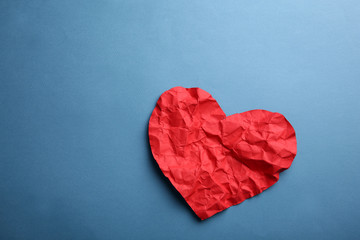 Crumpled paper heart on blue background