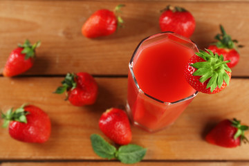 Glass of fresh strawberry juice on wooden background