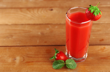 Glass of fresh strawberry juice on wooden background