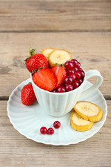 Cup of dessert with fresh fruits on wooden table, closeup