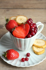 Cup of dessert with fresh fruits on wooden table, closeup
