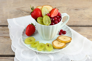 Cup of dessert with fresh fruits on wooden table, closeup