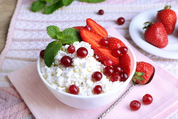 Bowl of cottage cheese with strawberry and cranberry on table, closeup