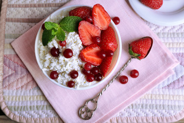 Bowl of cottage cheese with strawberry and cranberry on table, closeup