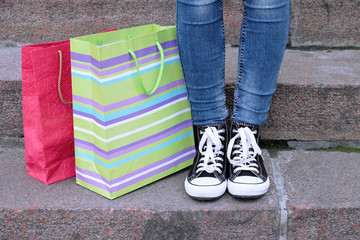 Female feet in gumshoes near shopping bag on  stone stairs