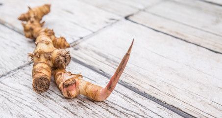 Galangal or Lengkuas roots over wooden background