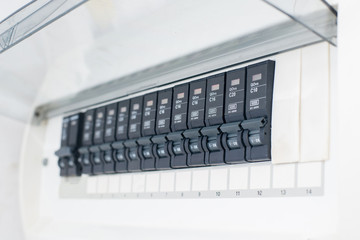 A row of switched off household electrical circuit breakers on a wall panel