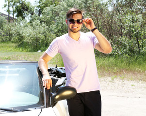 Young man standing near cabriolet, outdoors
