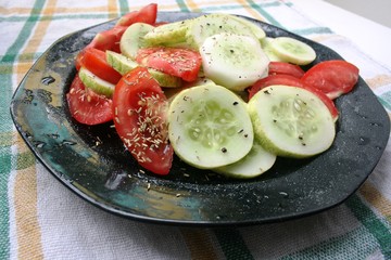 Cucumber and tomatoes sliced with fresh herbs on a plate